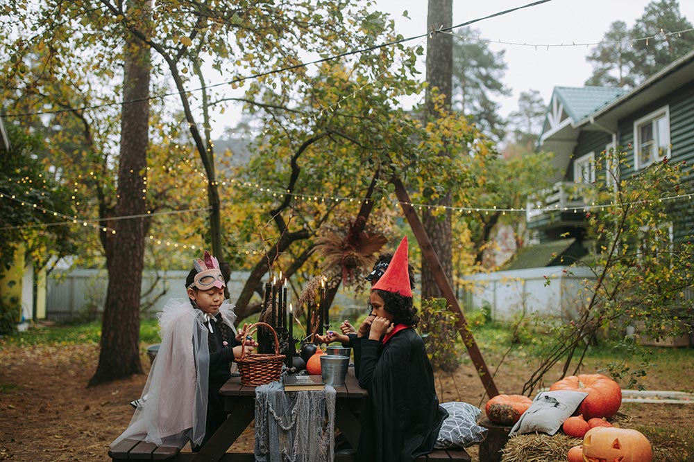 Halloween-Ambience-kids-in-halloween-costumes-eating-in-the-yard-with-halloween-decorations