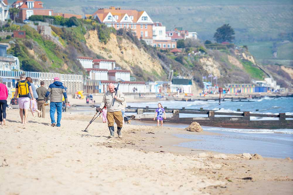 Man using metal detector at beach in UK.
