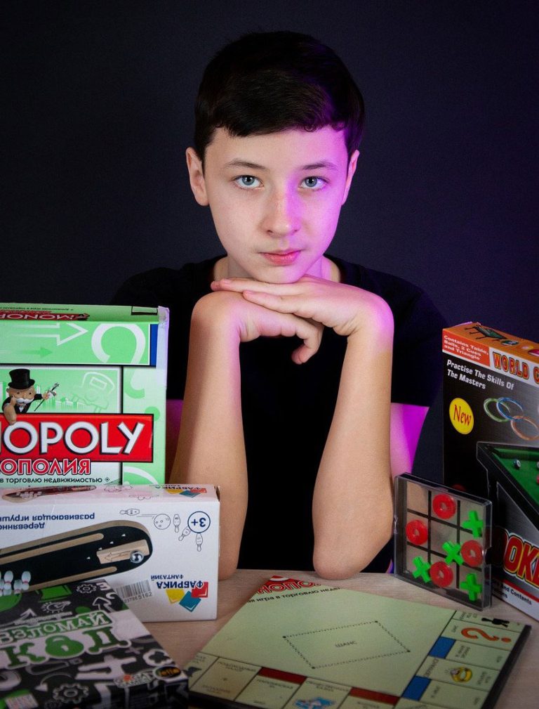 boy at table next to stack of board games boxes