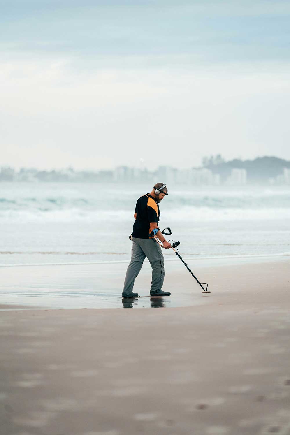 Man using metal detector at the beach engaged in Metal Detecting.