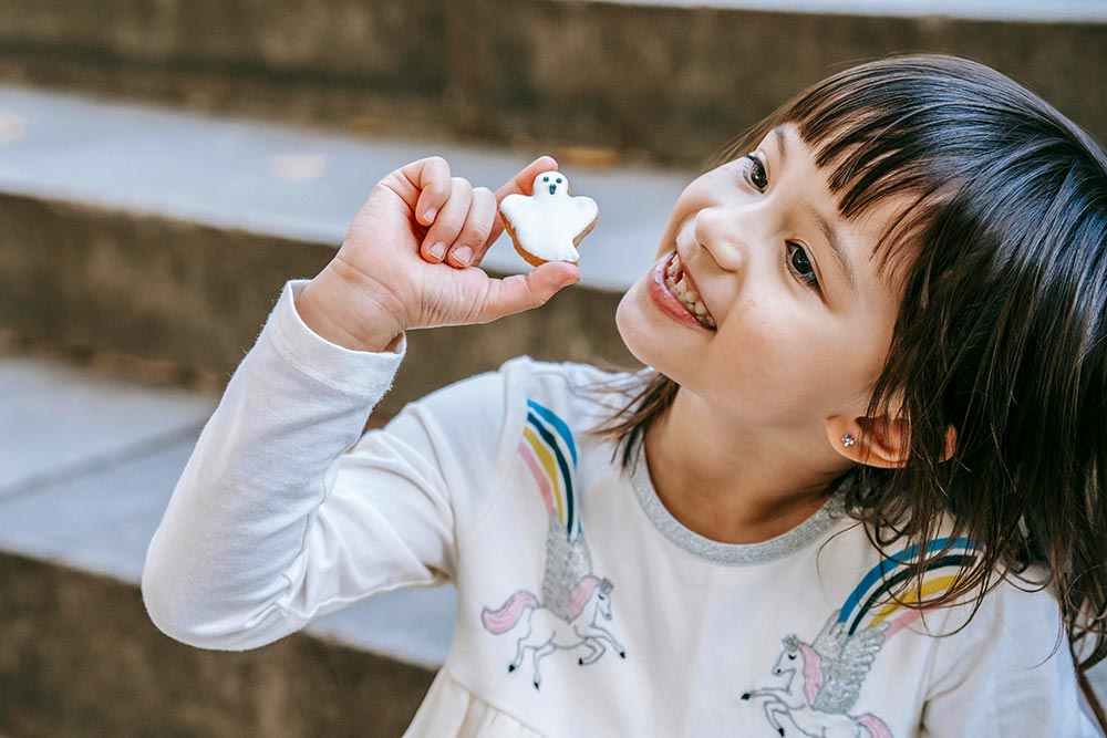 happy-girl-showing-ghost-shaped-halloween-cookie