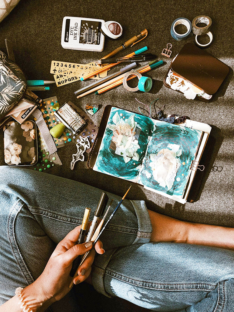 Junk Journaling. Woman sitting on floor painting in junk journal.